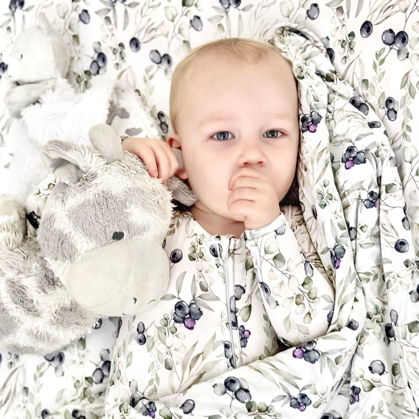 toddler using baby blankets in blueberry print while holding his toy