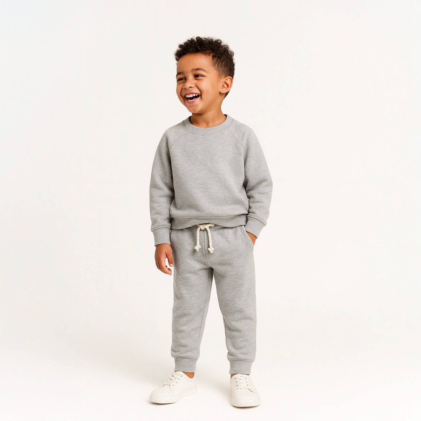 Child wearing a gray sweatshirt and pants set on a white background