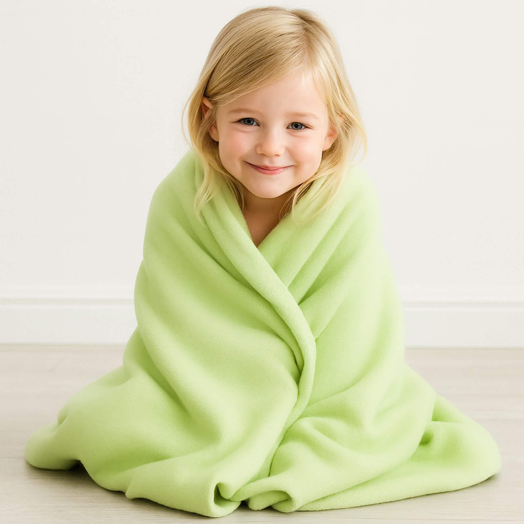 Child wrapped in a light green blanket on a white background