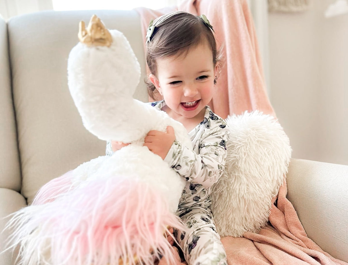 Baby girl holding stuffed animal while wearing Cuddle Sprouts pajamas