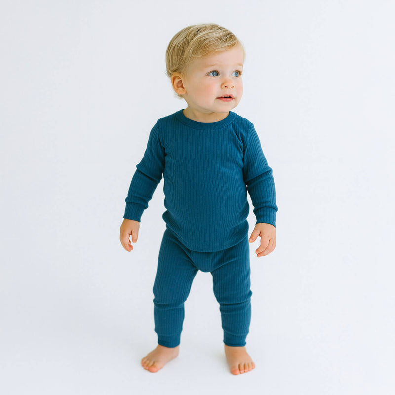 Child wearing a teal outfit on a white background