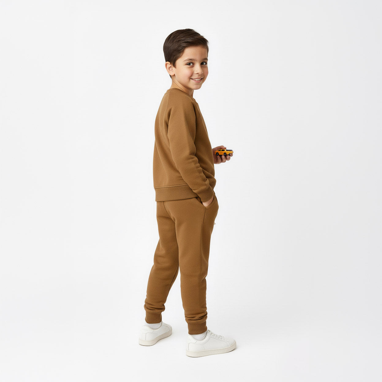 Child wearing a brown tracksuit on a white background