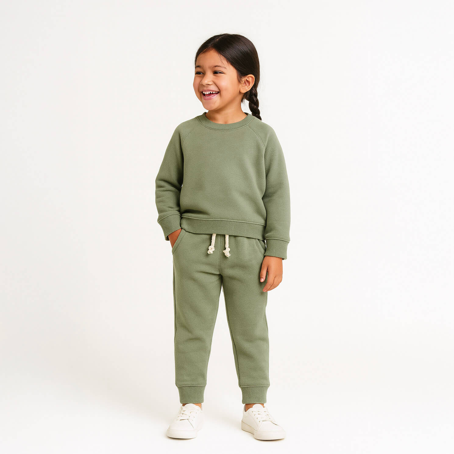 Child wearing a green sweatshirt and pants set on a white background