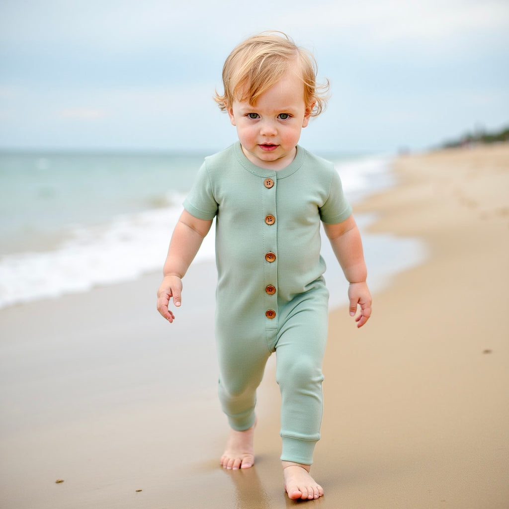 Toddler walking wearing green romper 