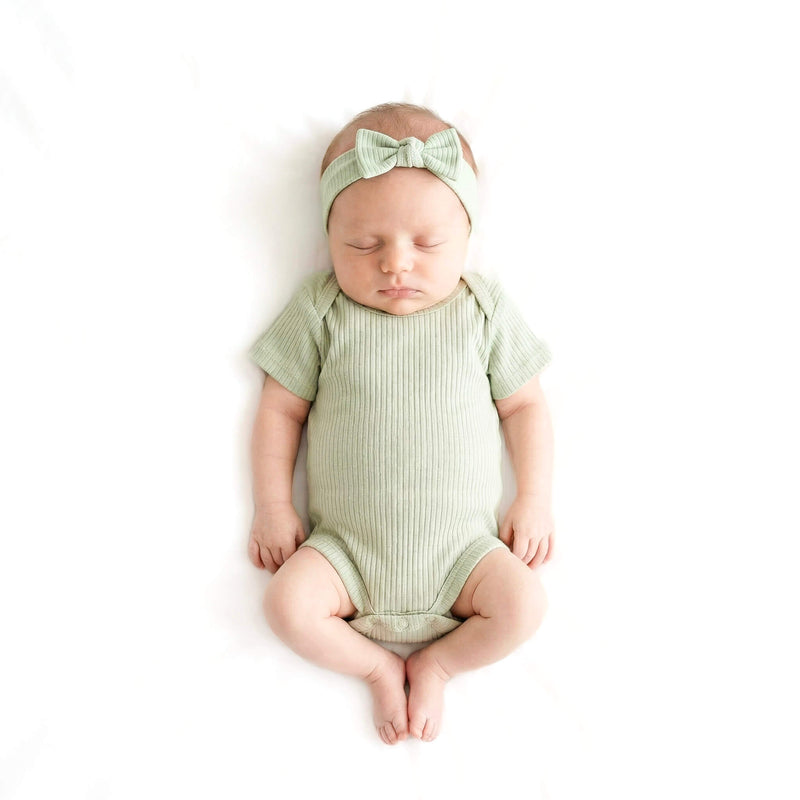 baby wearing green bodysuit