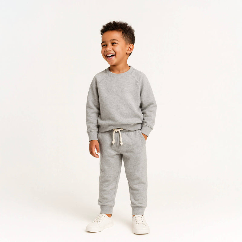 Child wearing a gray sweatshirt and pants set on a white background