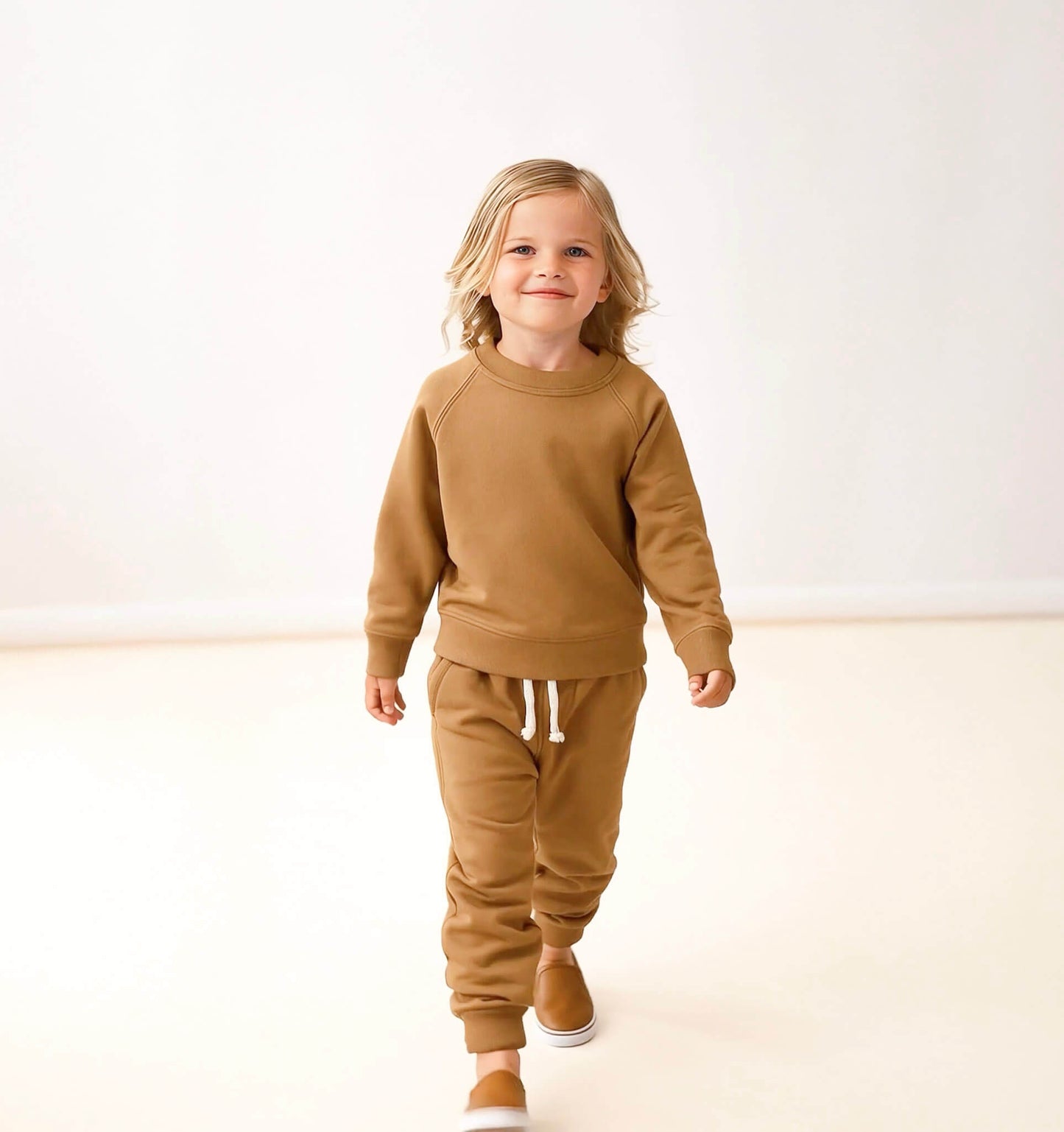Child wearing a brown outfit on a white background