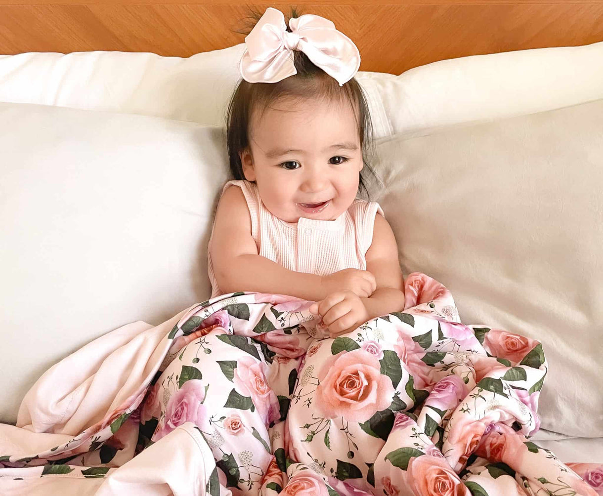 Baby girl holding her favorite Tencel Lyocell baby blanket in roses 