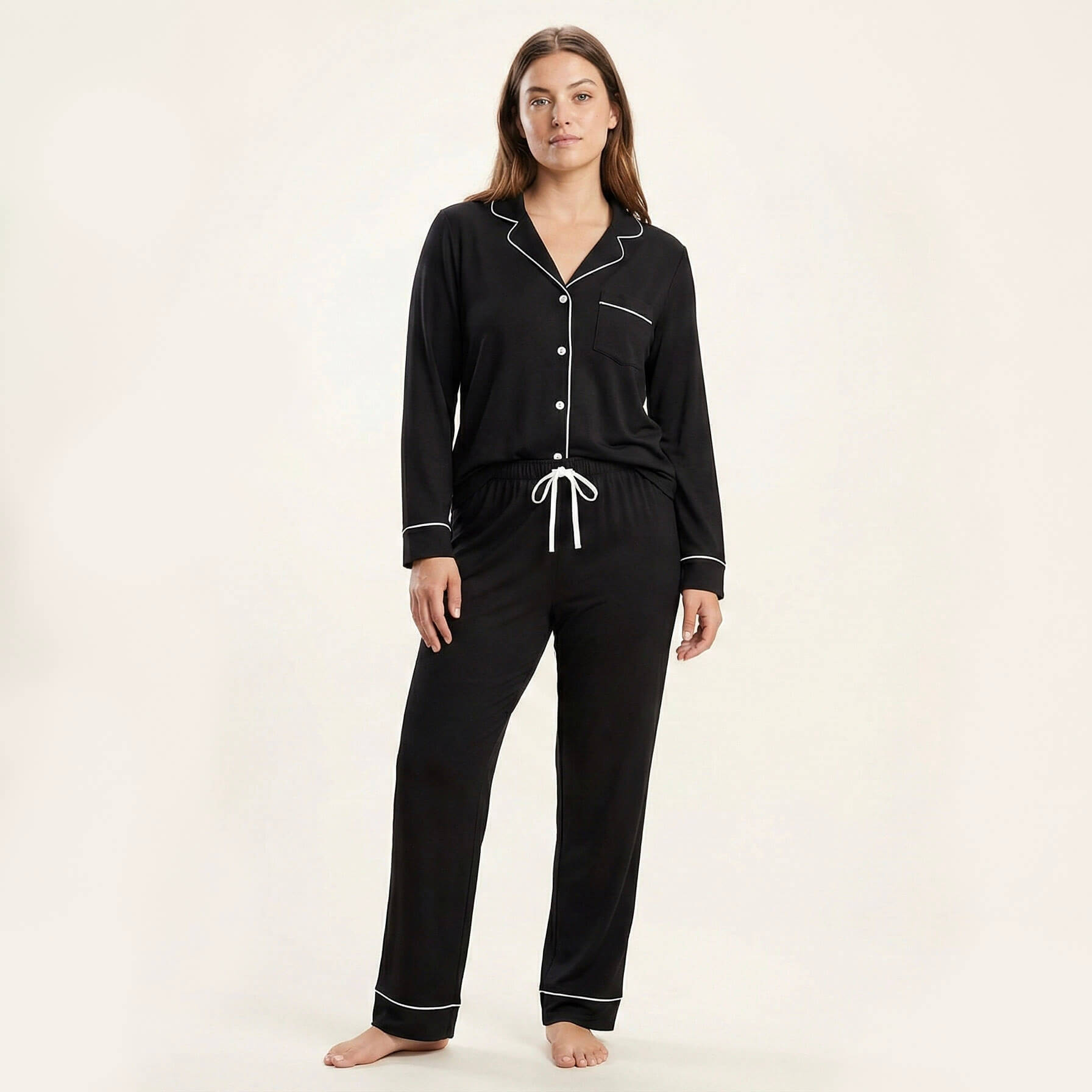 Woman wearing black pajamas with white piping on a white background