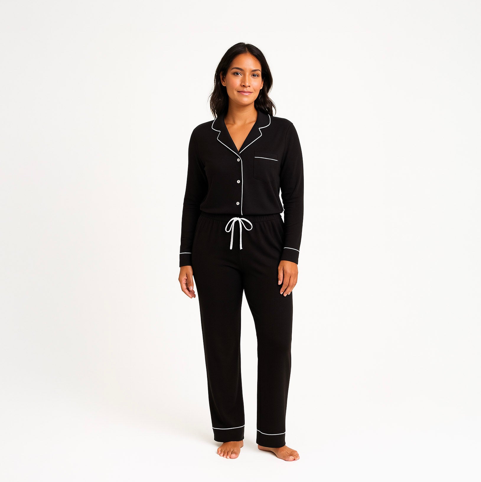 Woman wearing a black pajama set with white piping on a white background