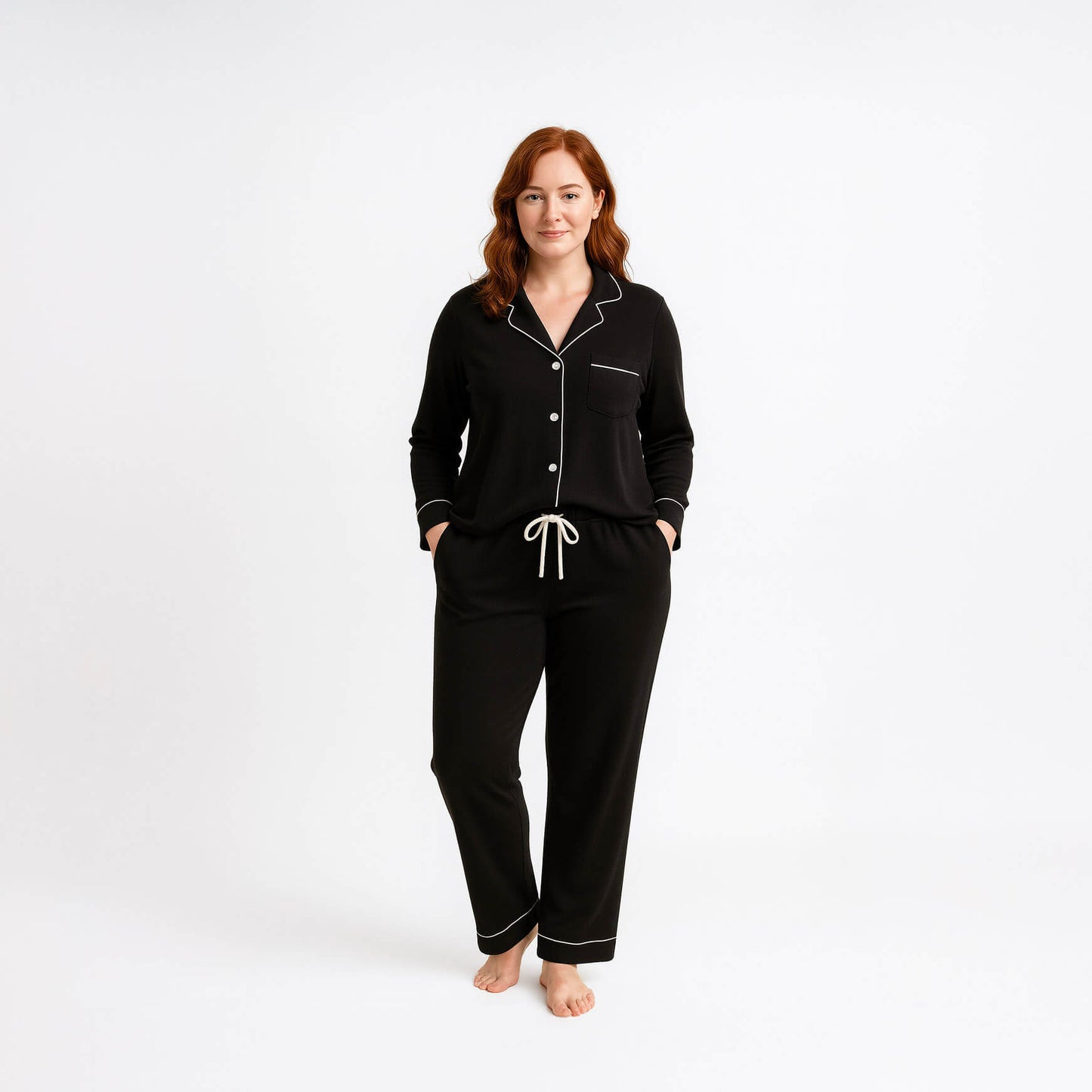 Woman wearing a black pajama set with white piping on a white background