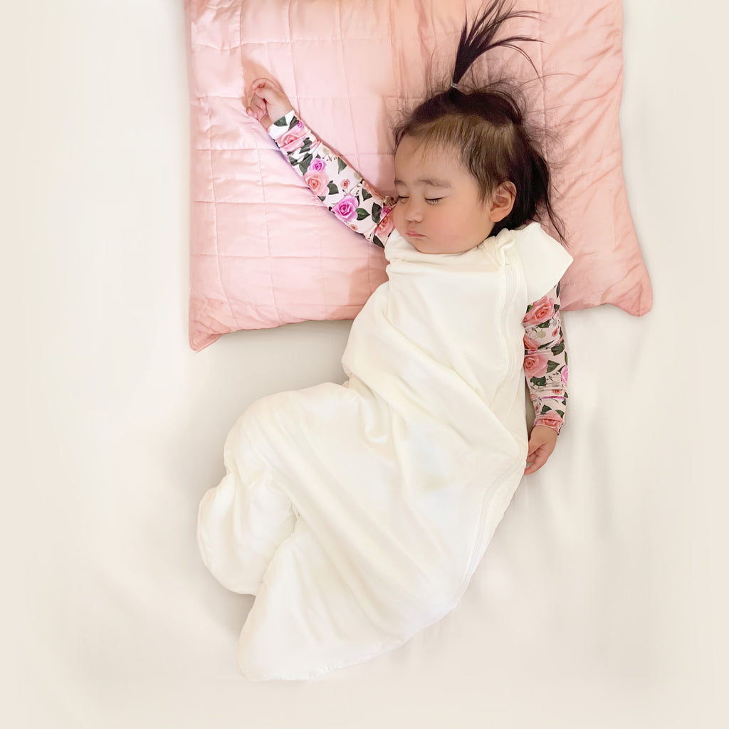 baby sleeping while wearing white sleep sack