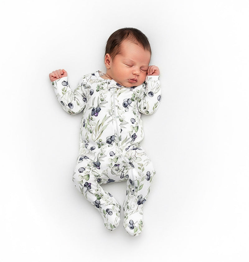 Newborn baby wearing a blueberry onesie on a white background