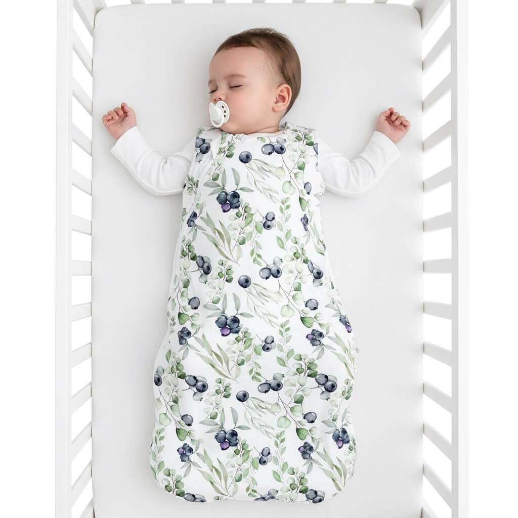 Baby sleeping in a crib with a blueberry-patterned sleep sack