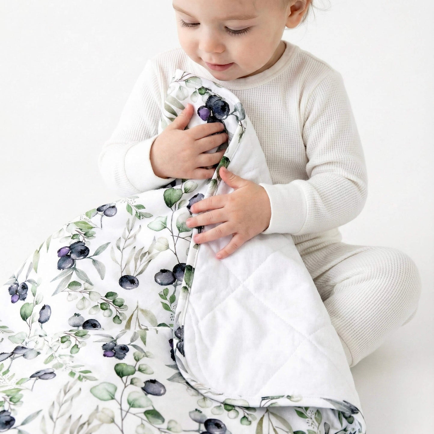 Child holding a blueberry-patterned blanket 