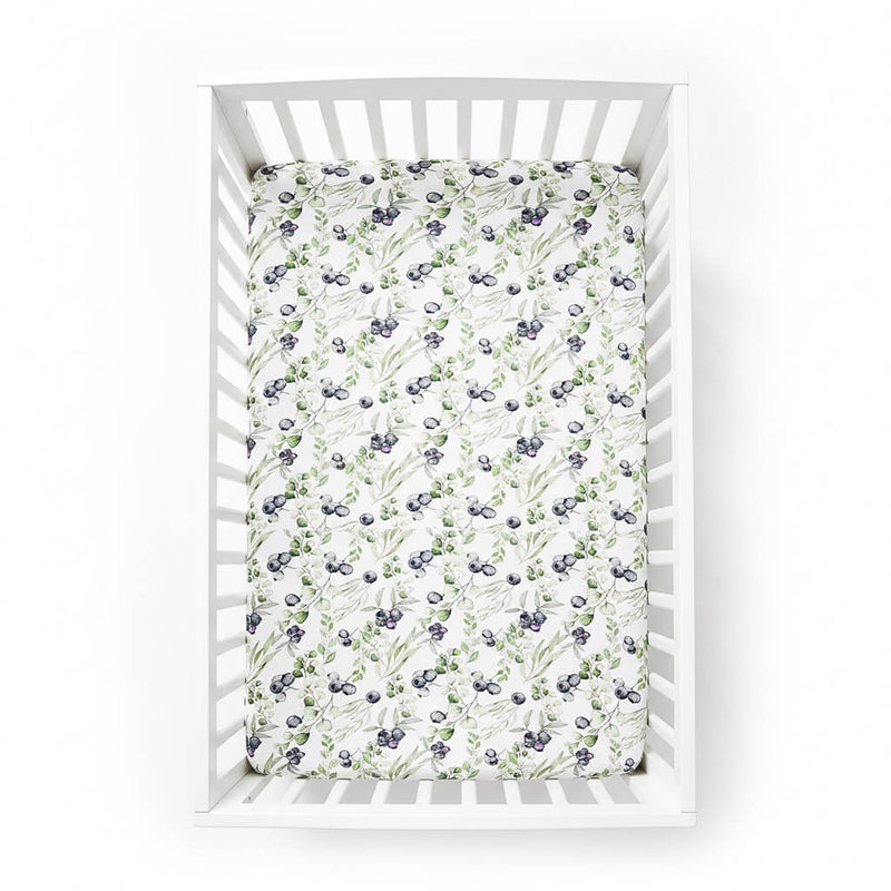 blueberry patterned crib sheet on a white crib