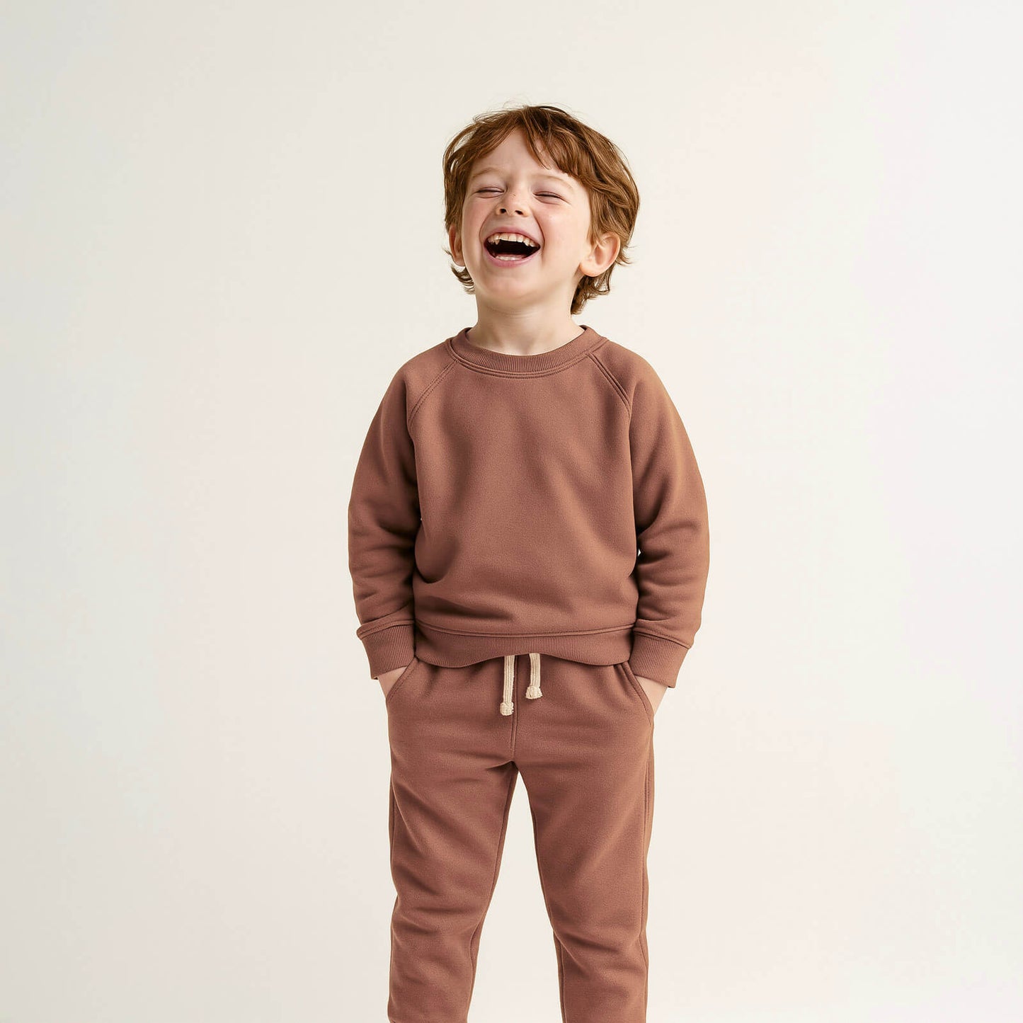 Child wearing a brown sweatshirt and pants on a light background