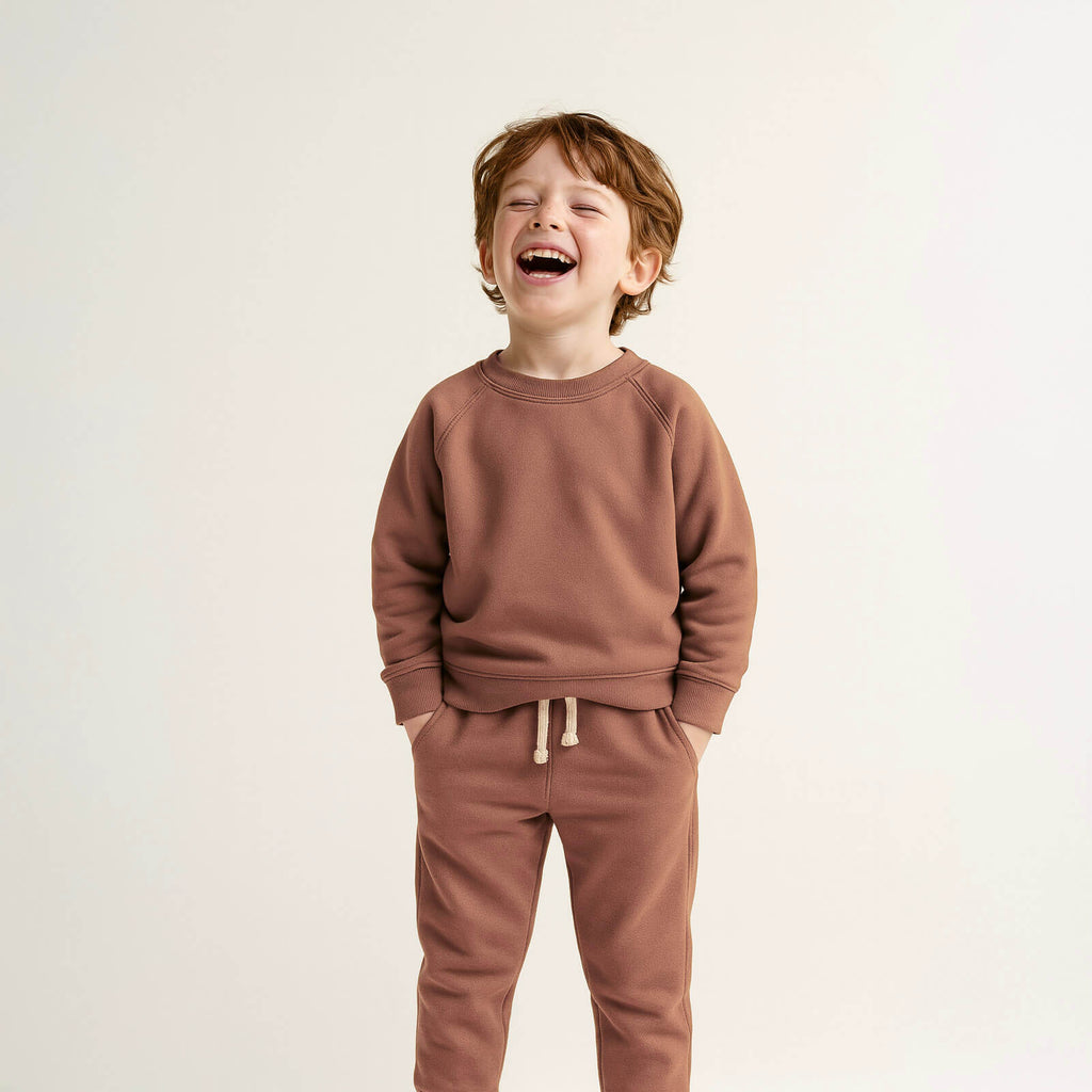 Child wearing a brown sweatshirt and pants on a light background