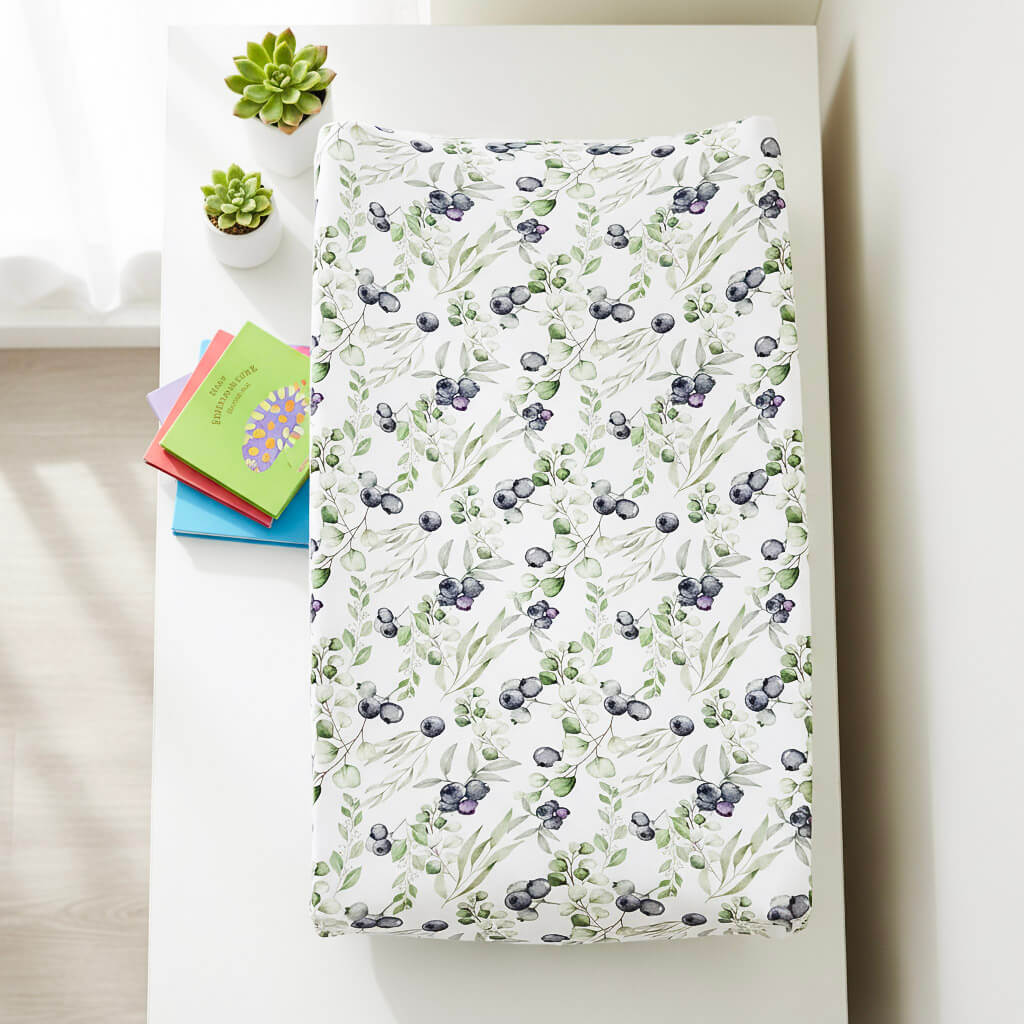 blueberry patterned changing pad on a white surface with books and succulents in the background