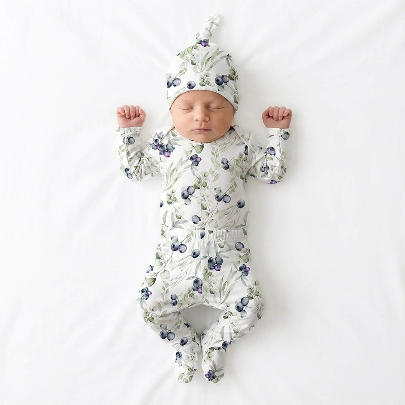 Baby in floral onesie and hat lying on a white background