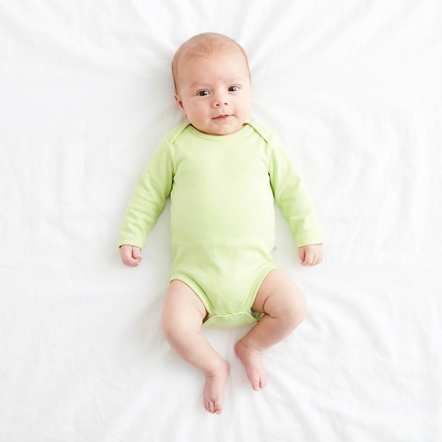 Baby wearing a green onesie on a white background