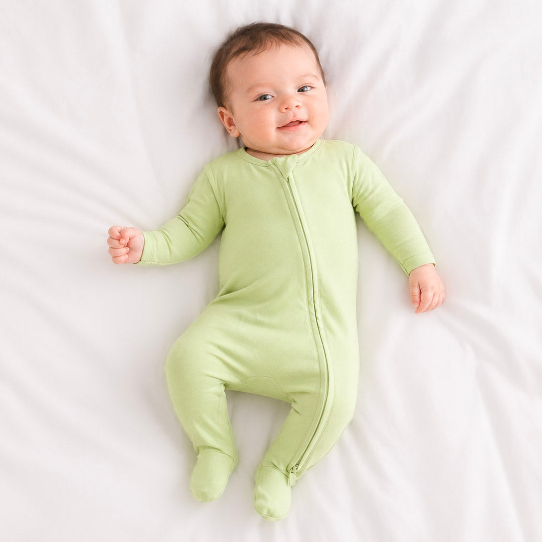 Baby wearing a light green onesie on a white background