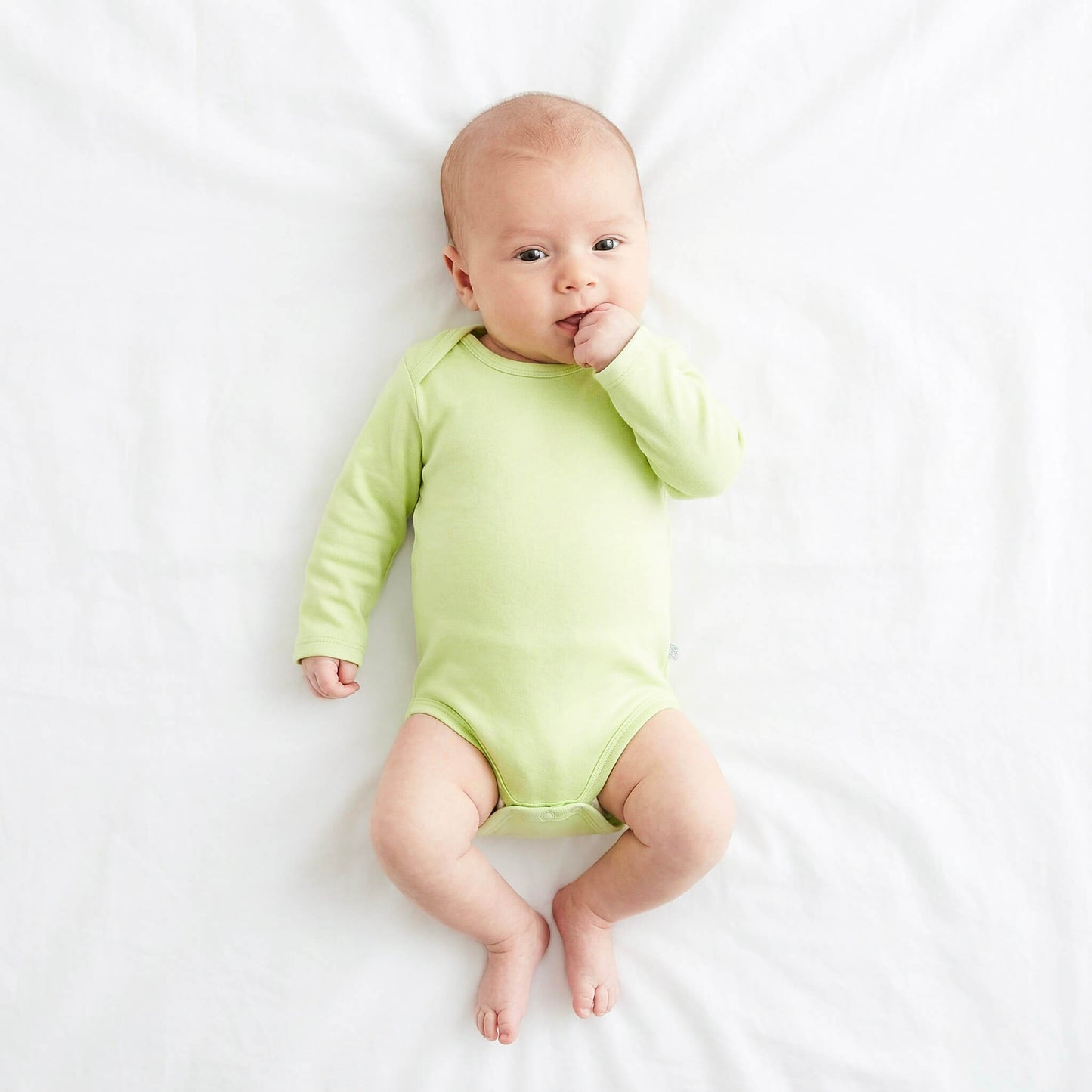 Baby wearing a light green onesie on a white background