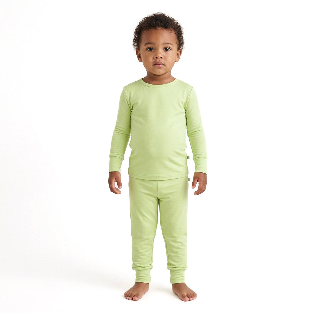 Child wearing a light green pajama set on a white background