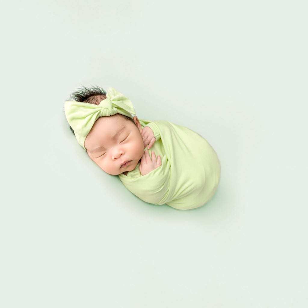 newborn wearing green swaddle set