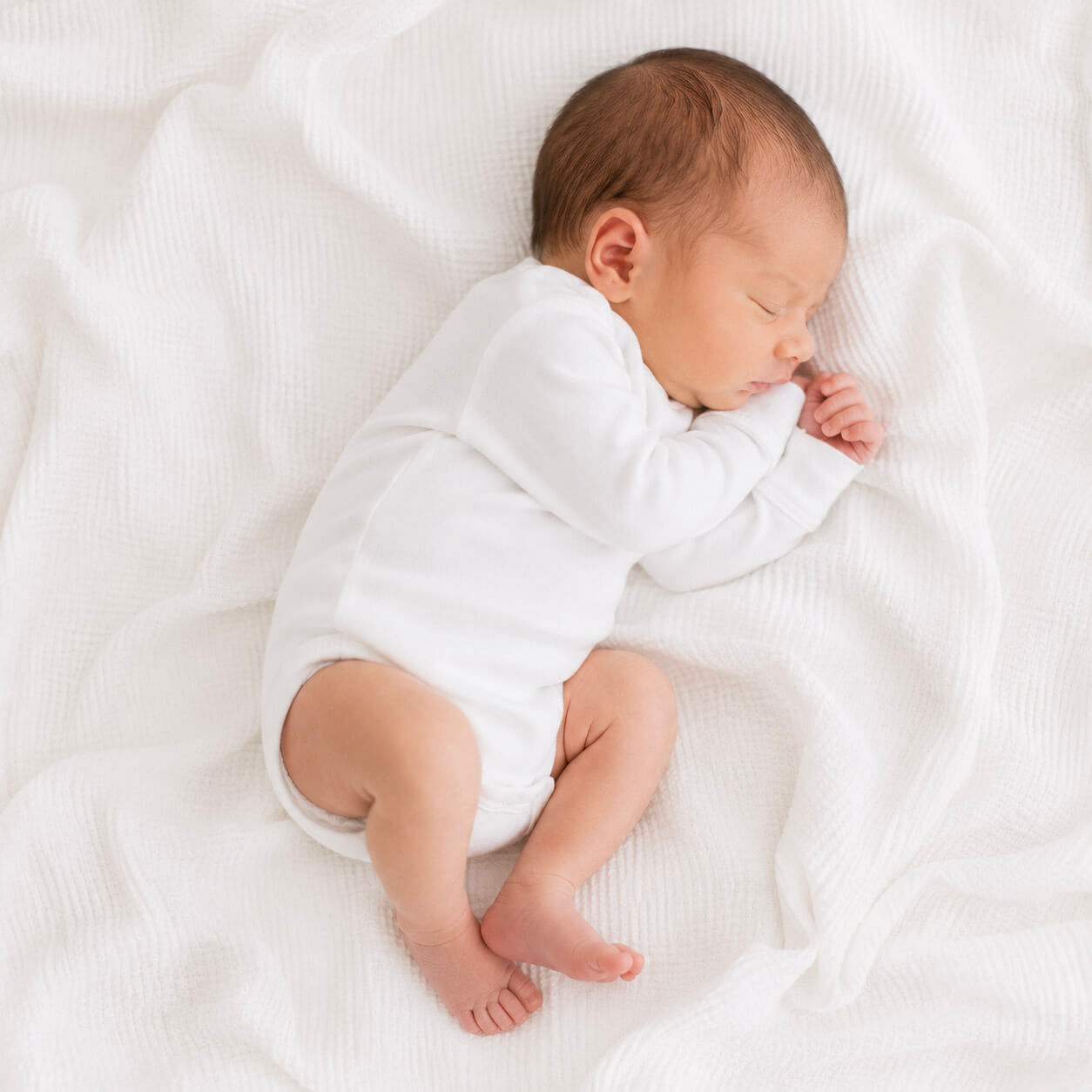 Newborn baby sleeping peacefully on a white blanket