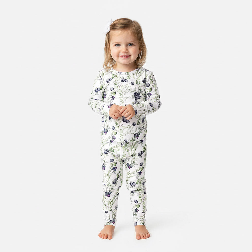 Child wearing a blueberry long sleeve pajama on a white background.