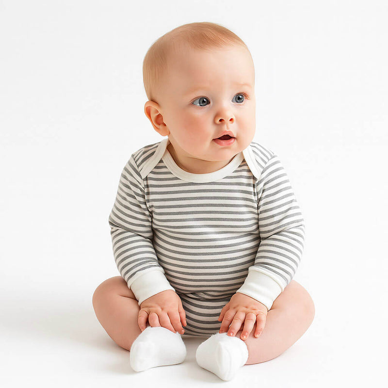 Baby wearing a striped onesie sitting on a white background
