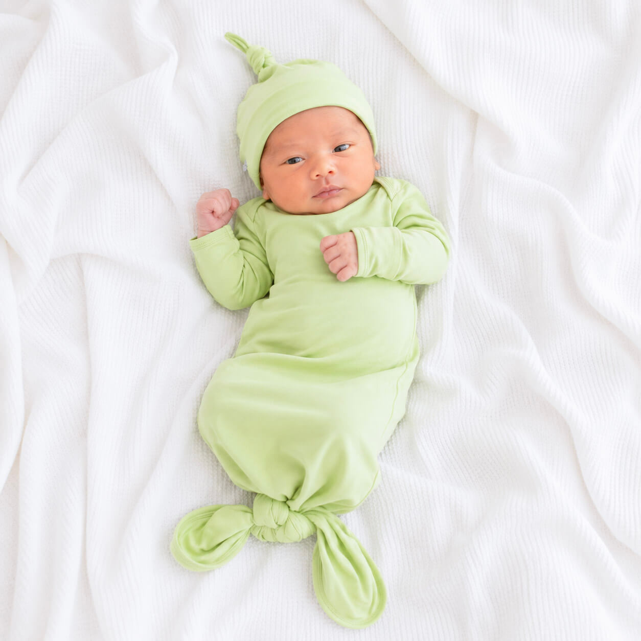 Newborn wearing green gown and beanie 