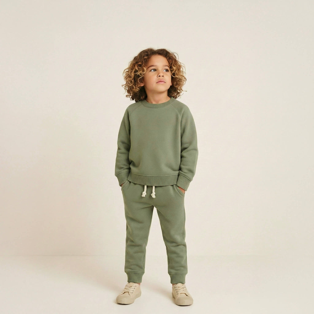 Child wearing a green outfit on a plain background