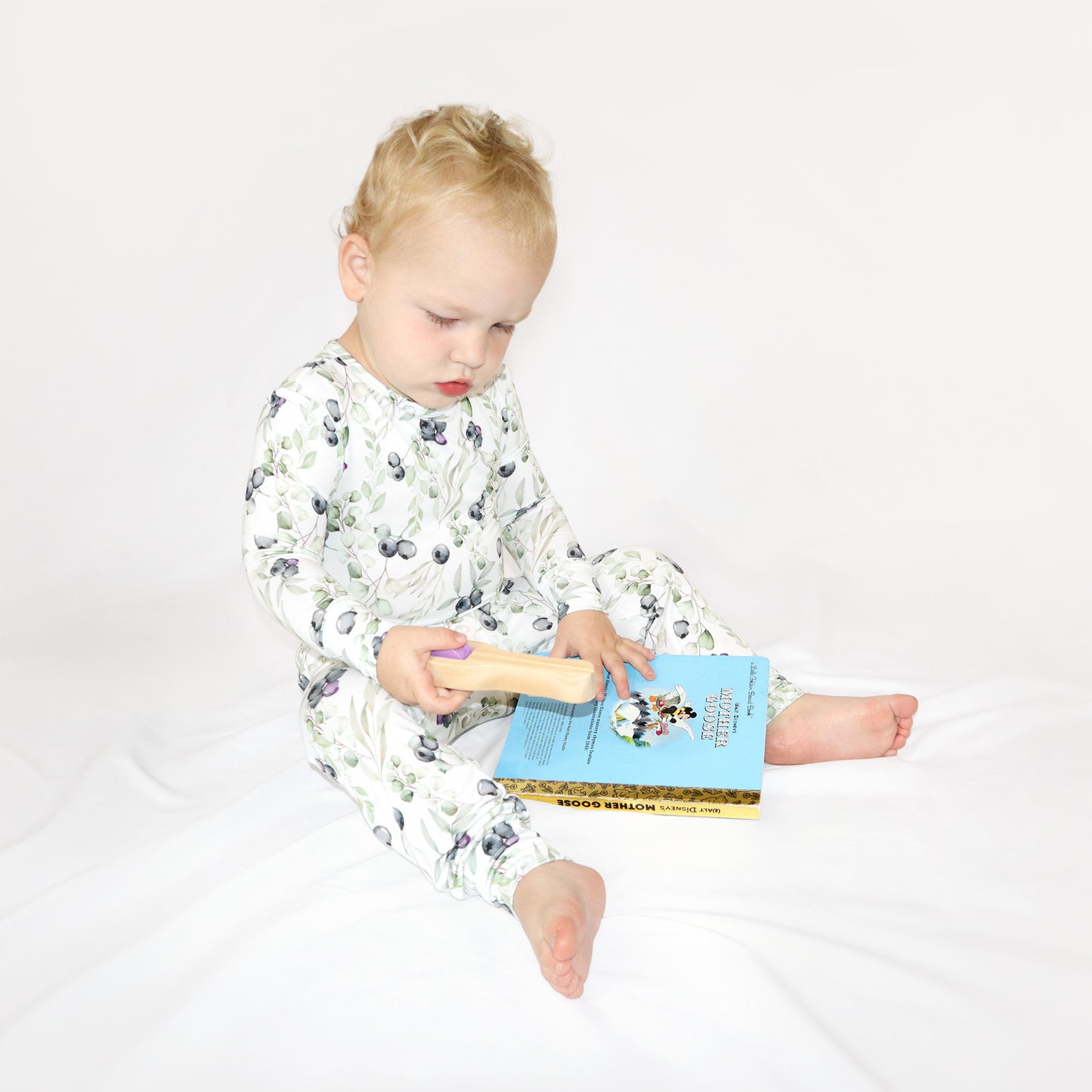 Toddler boy wearing blueberries 2 piece baby pajamas while reading his book