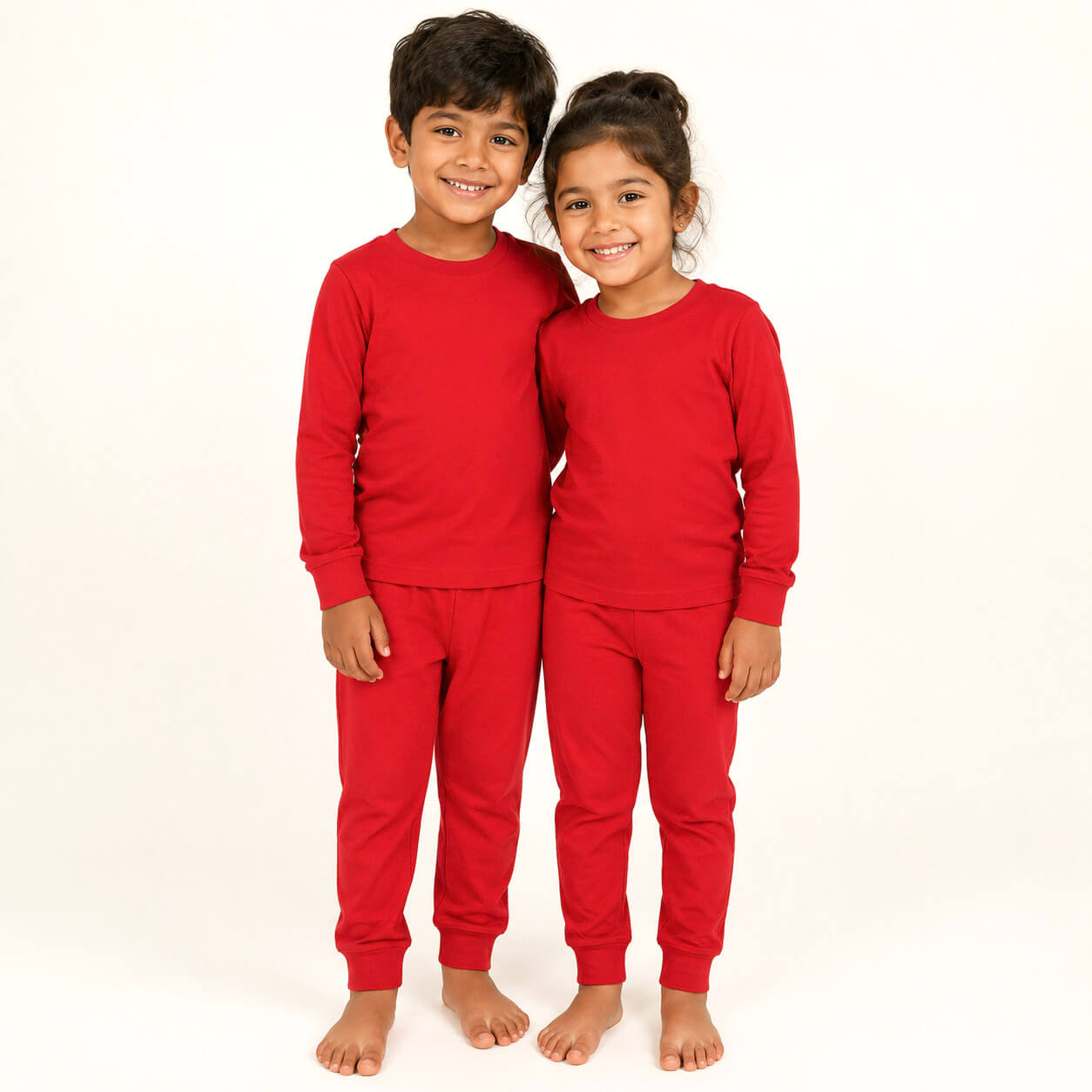 Two children wearing red pajamas on a white background
