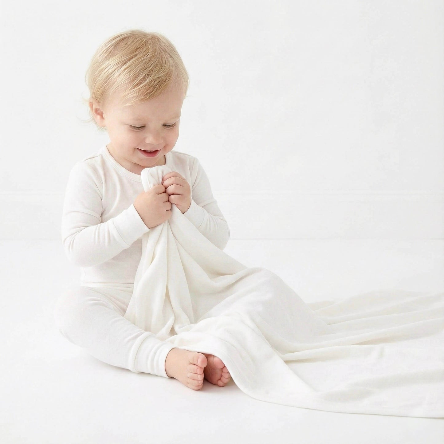 Child holding a white blanket on a light background