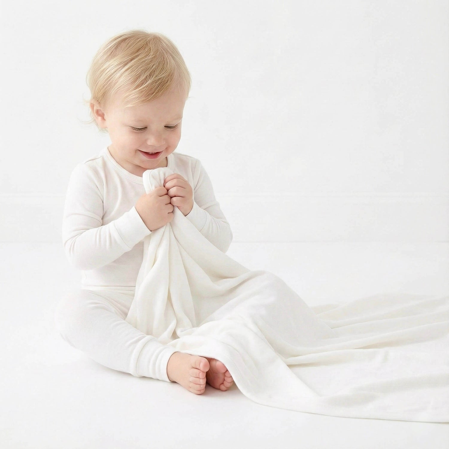 Child holding a white blanket on a light background