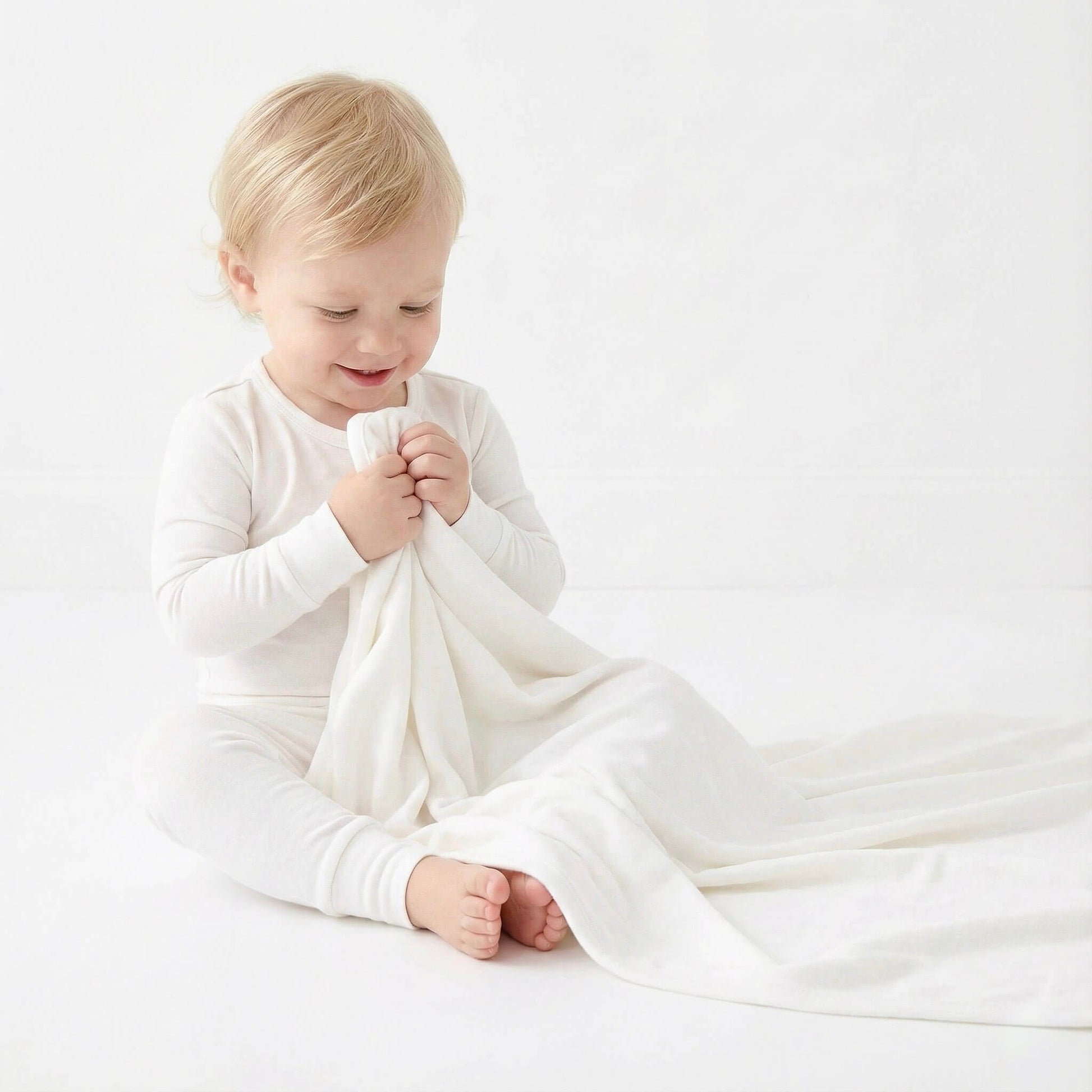 Child holding a white blanket on a light background