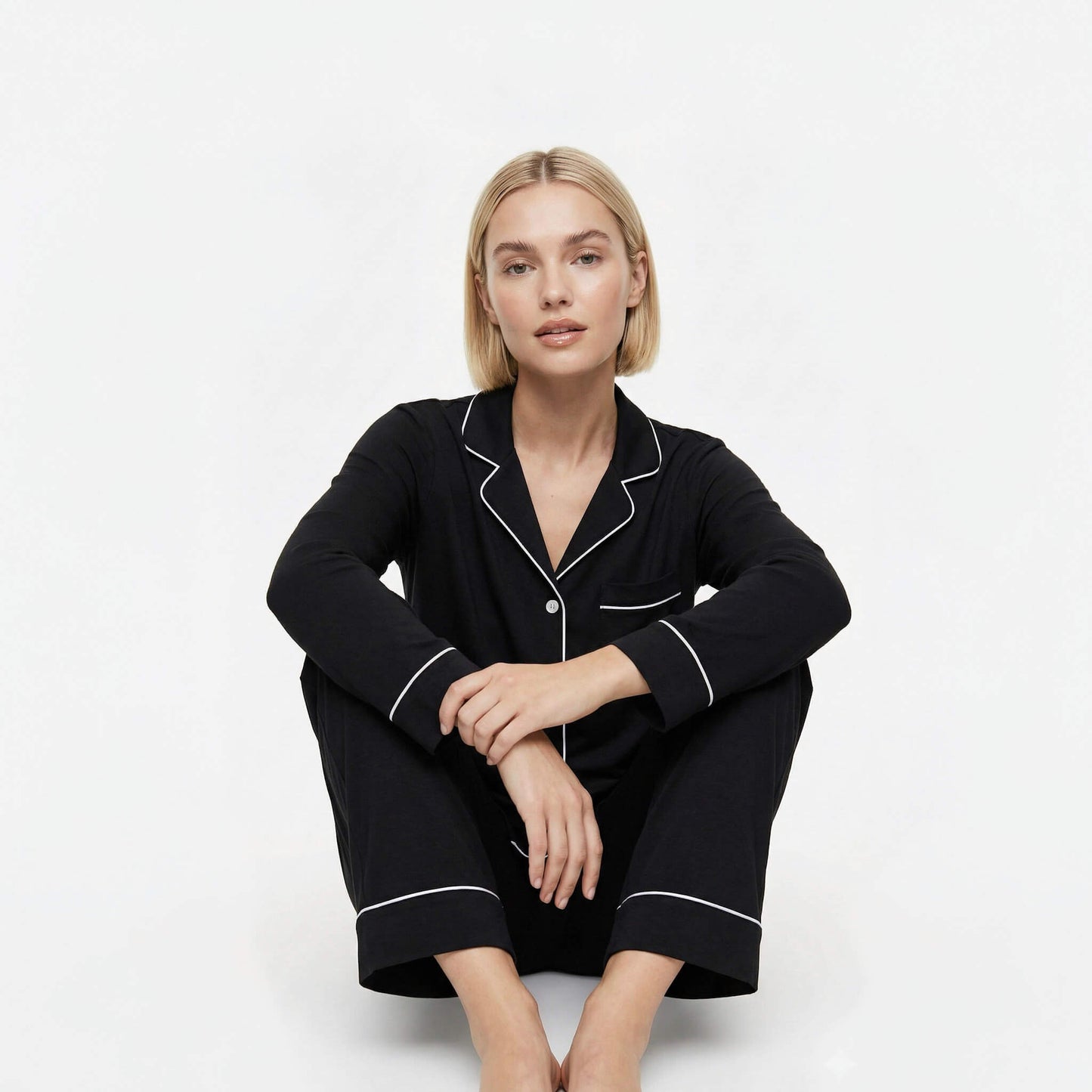 Woman wearing black pajamas with white piping on a white background